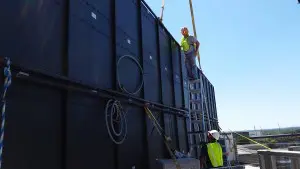 A man on a ladder next to a black wall.