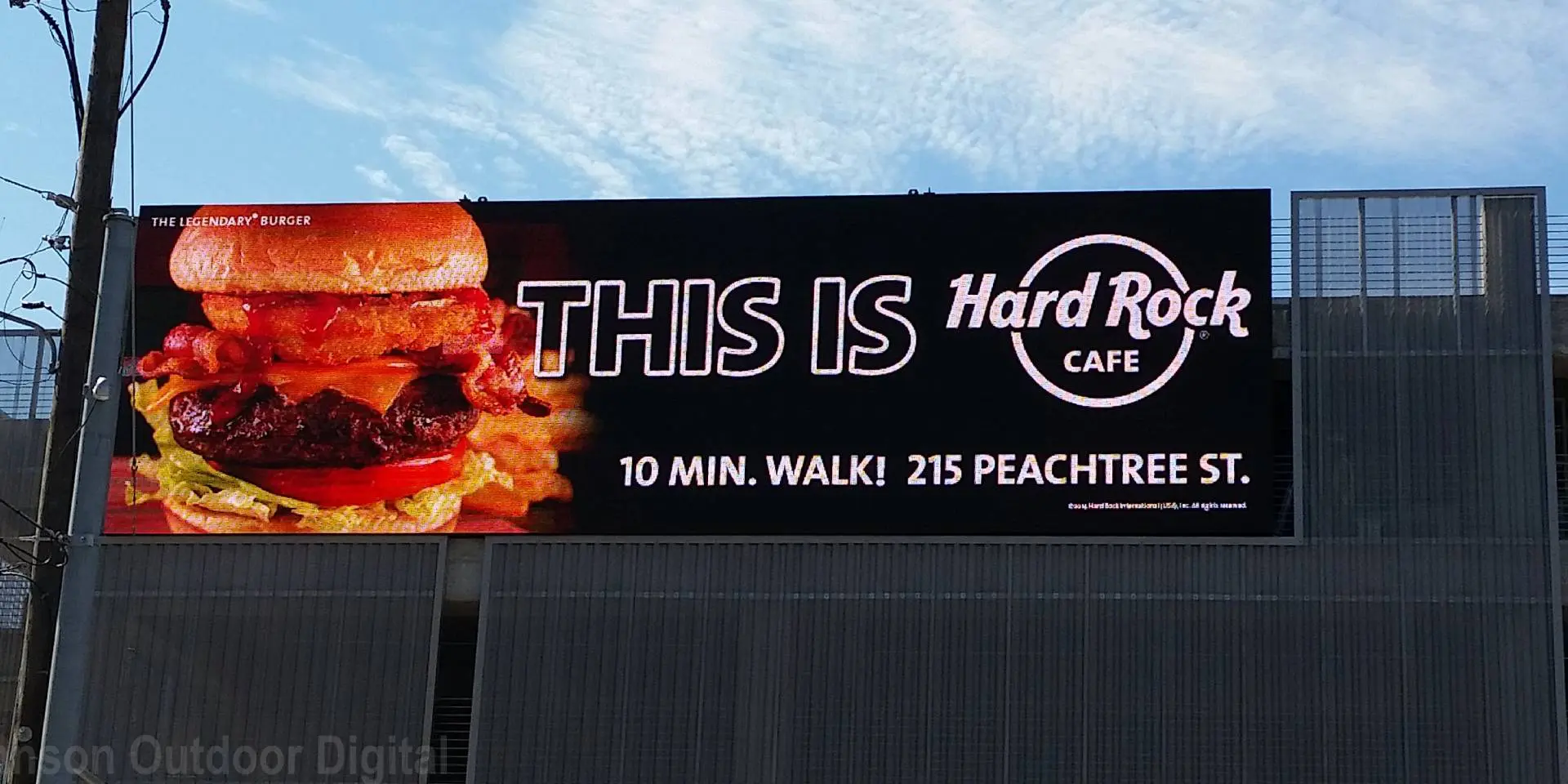 A billboard with a burger and the words " this is hard rock cafe ".