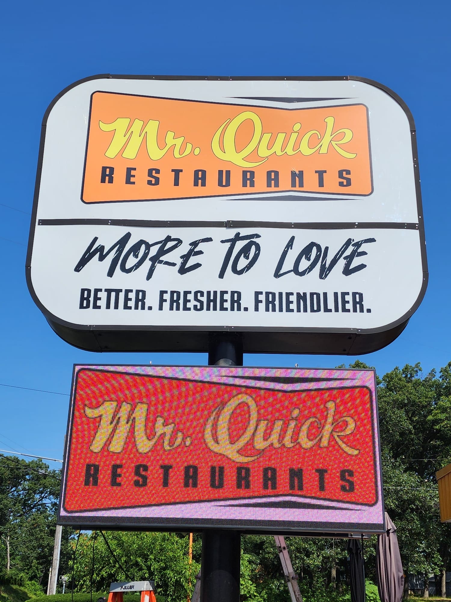 A sign for mr. Quick restaurants in front of trees