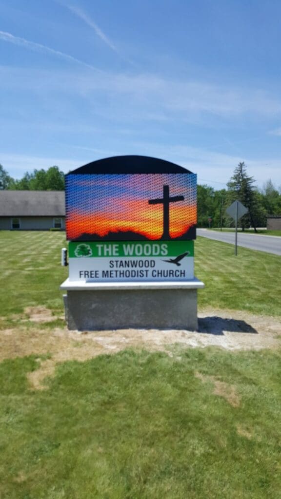 A sign that says the woods, stanwood free methodist church.